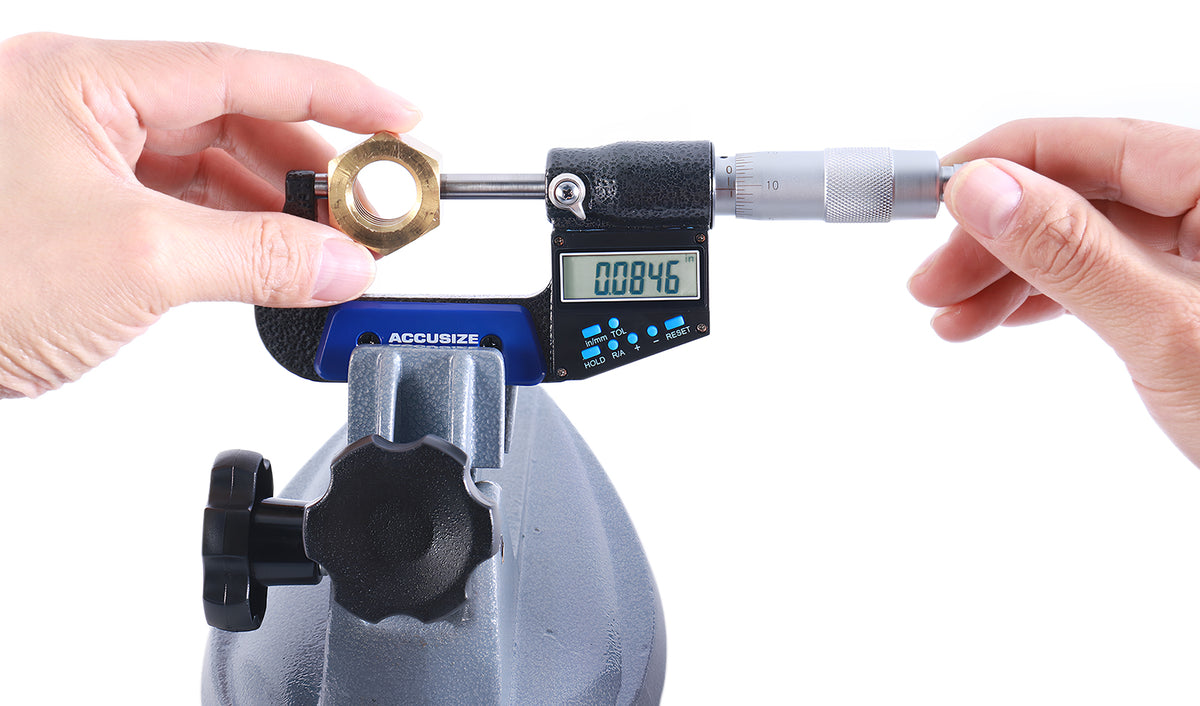 Electronic digital outside micrometer measuring hex nut with both hands, large LCD showing accurate reading, ideal for machining and inspection tasks