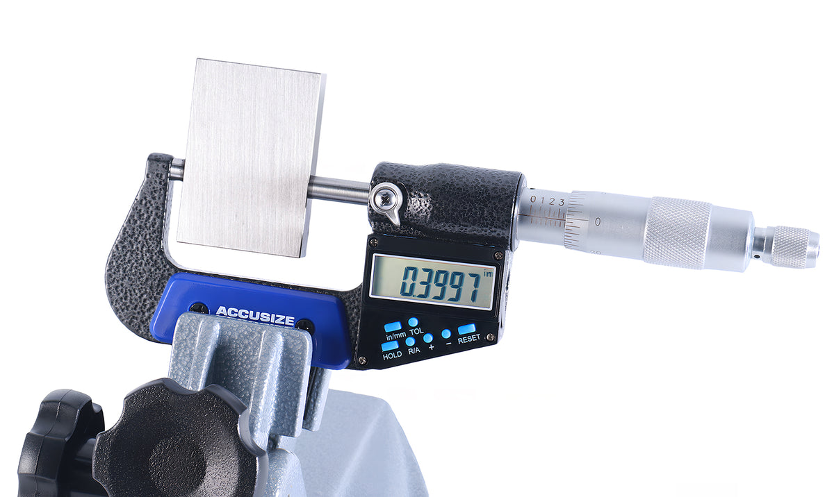 Electronic digital outside micrometer measuring gauge block on stand, large LCD display showing precision reading, high accuracy metalworking inspection tool